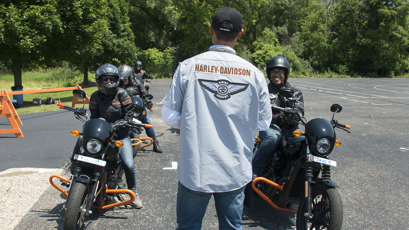 Personas aprendiendo a conducir una moto en una zona de enseñanza